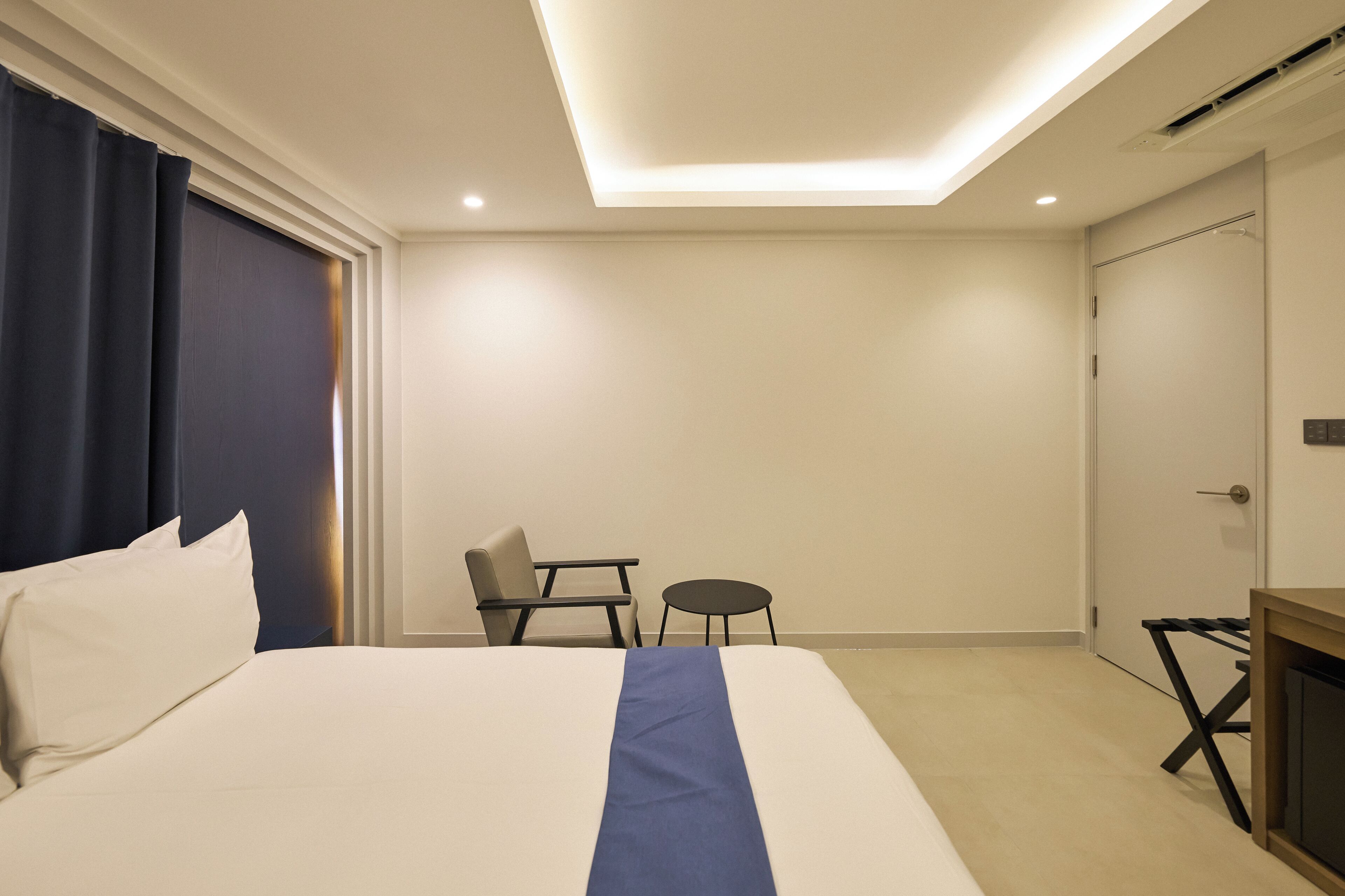 Une chambre d’hôtel avec un lit, une chaise, une petite table et un bureau.