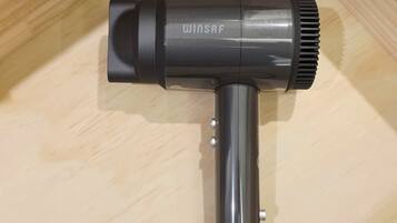 A black Winsaf hair dryer with a cylindrical shape and a ribbed nozzle, placed on a wooden surface.