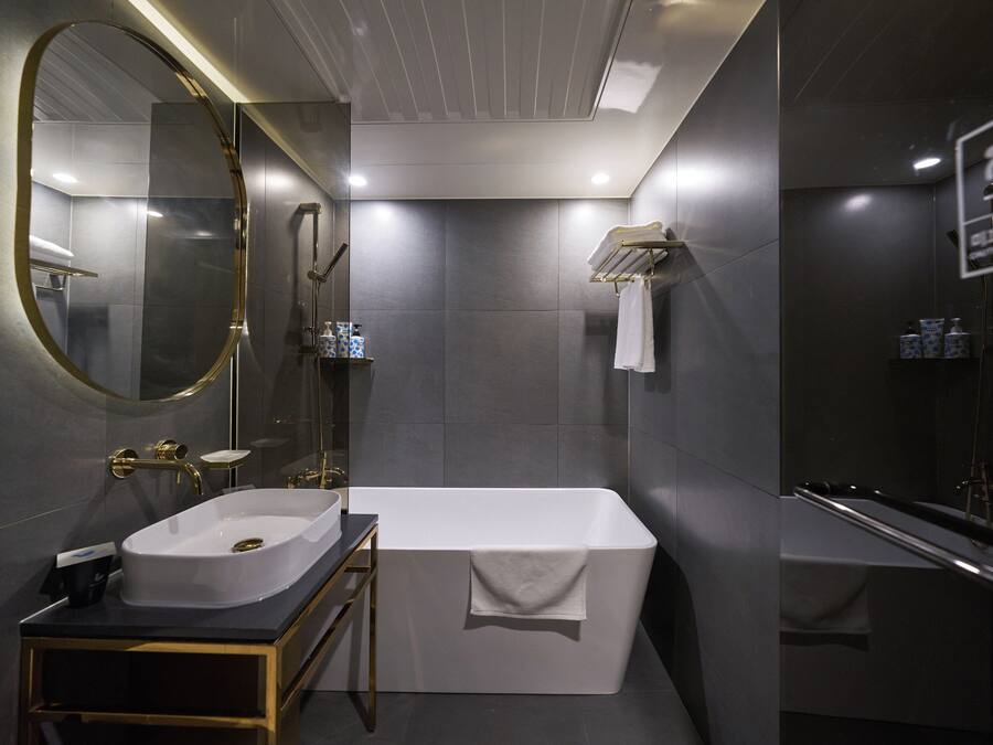 Un baño moderno con una bañera independiente, un espejo grande y un lavamanos.