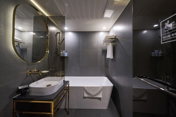 A modern bathroom with a freestanding bathtub, a large mirror, and a vanity with a sink.