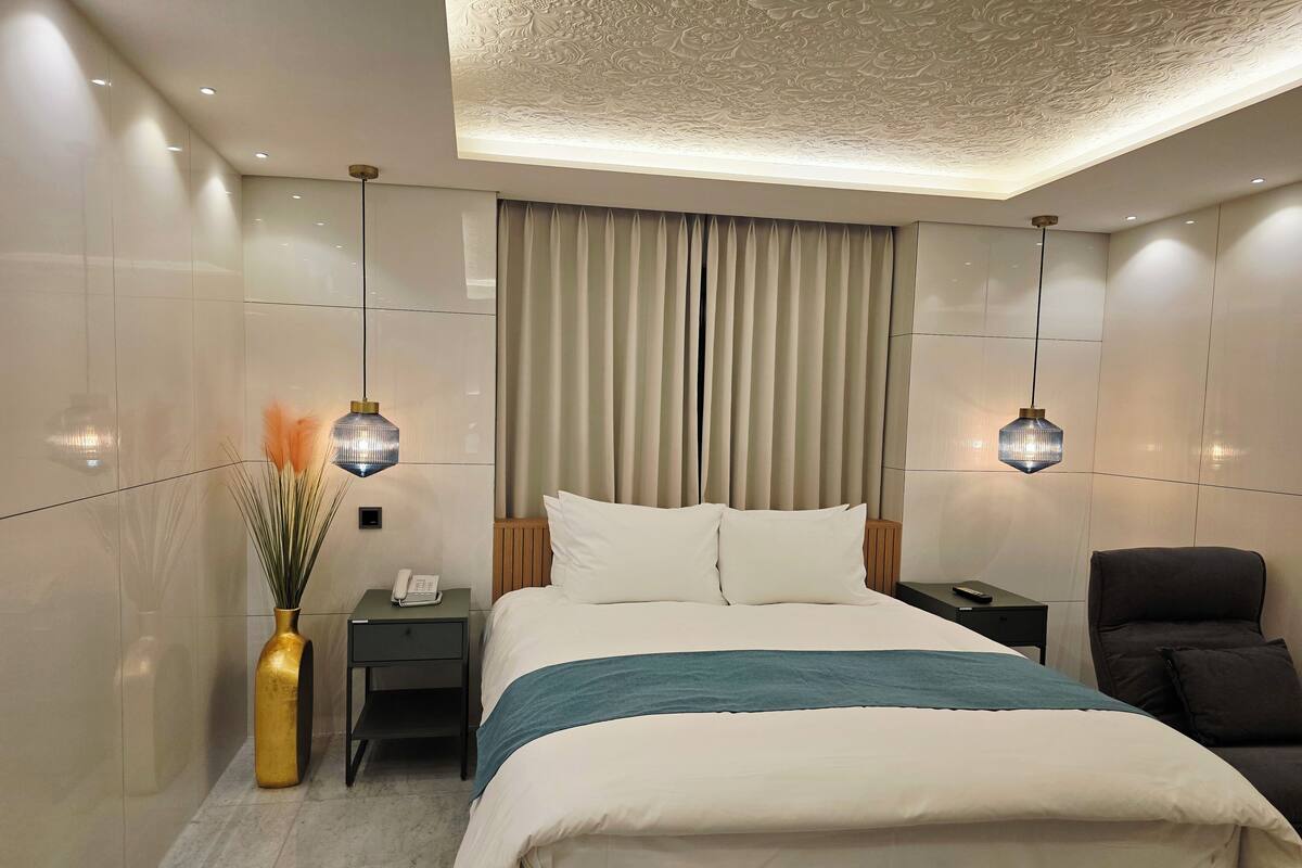 A modern hotel room with a large bed, bedside tables, a desk, and a chair.