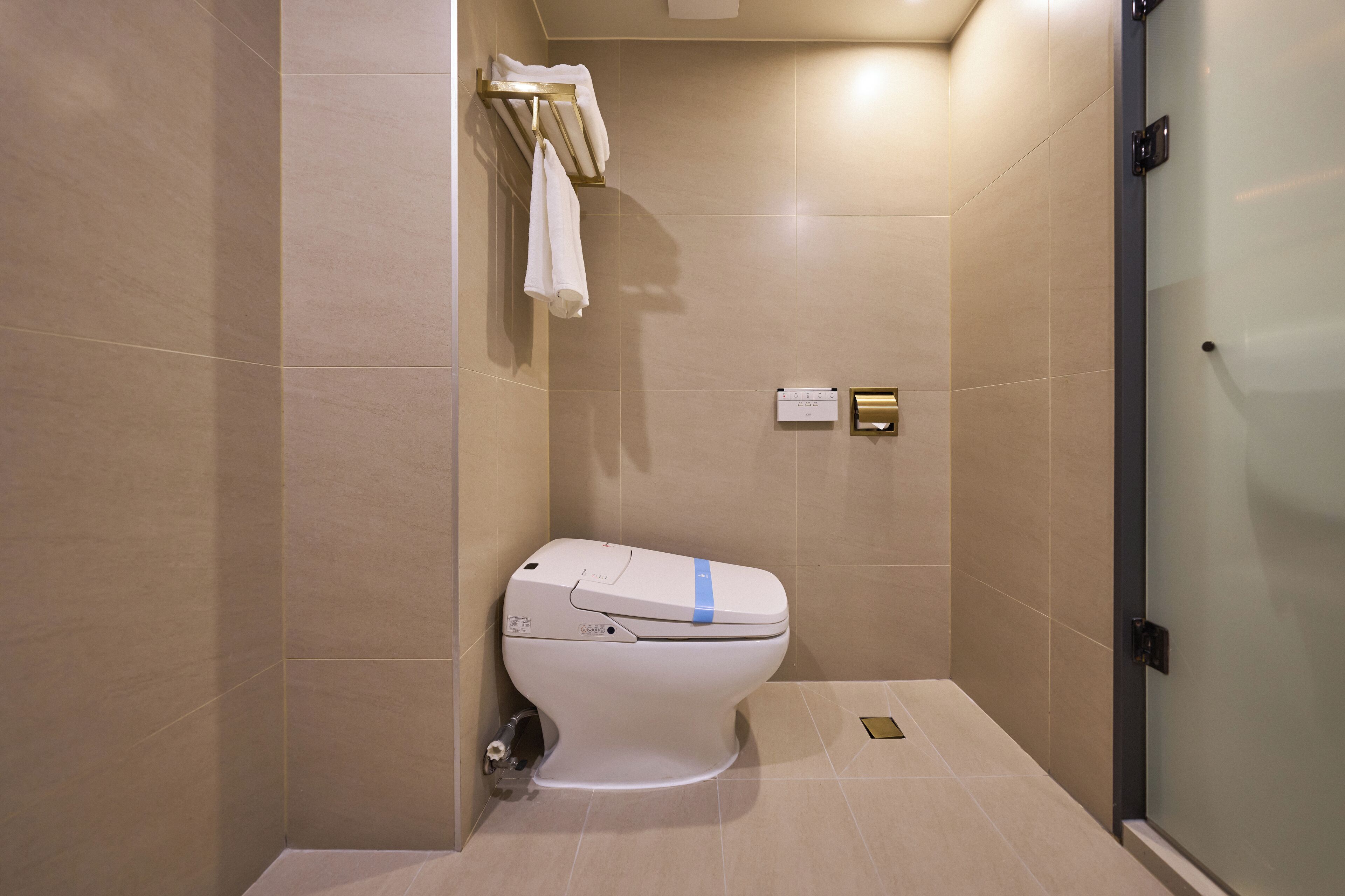 Un baño moderno con inodoro, toallero y panel de control.