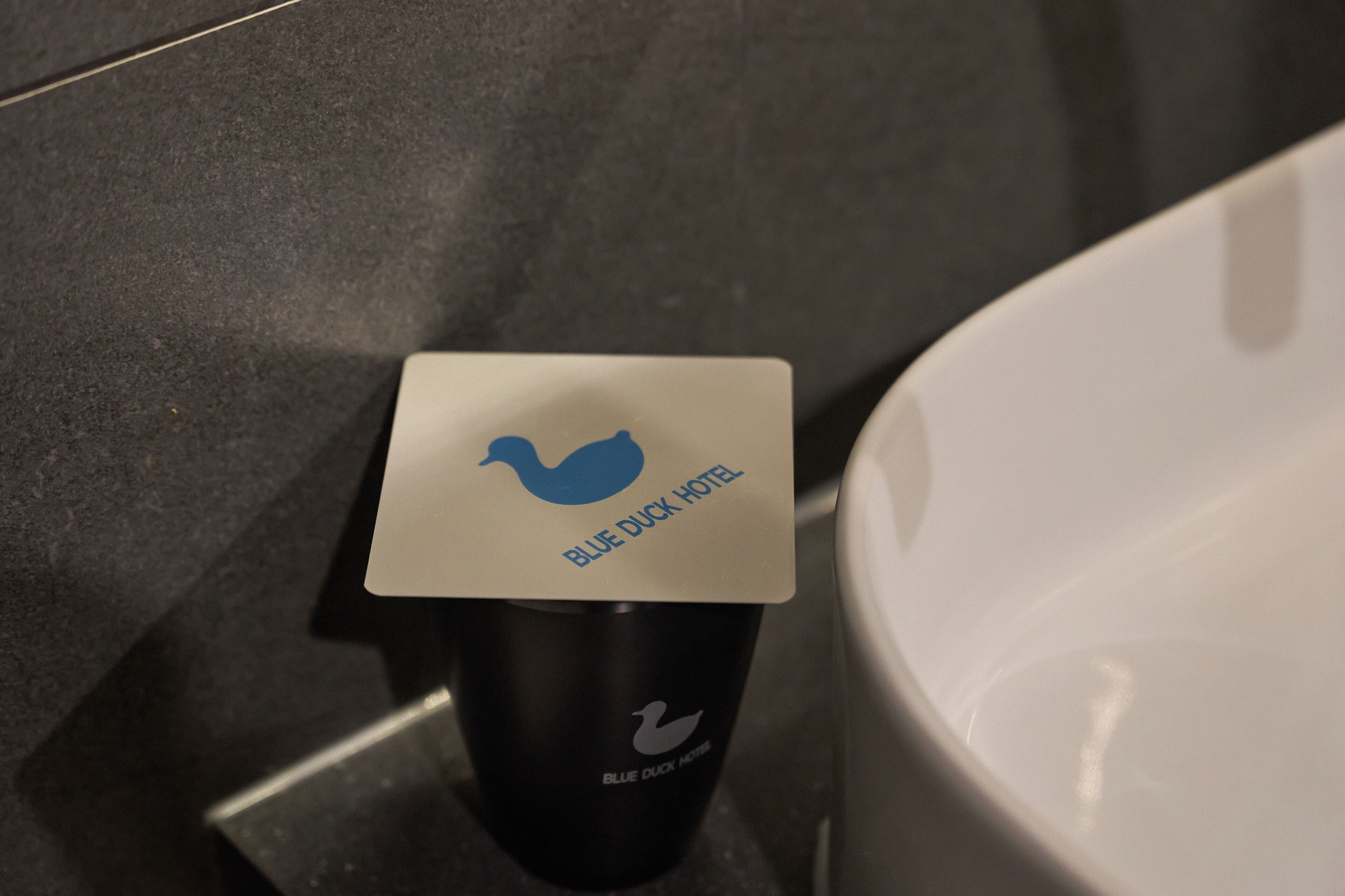 A black tumbler with a white label that reads "BLUE DUCK HOTEL".