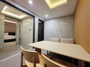 A modern hotel room with a large bed, a separate bathroom, and a dining area with a table and chairs. - BlueDuck Hotel (Seoul)