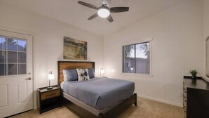 A bedroom with a bed, nightstands, a ceiling fan, and a window with blinds.