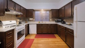 A compact kitchen with dark wooden cabinets, a white stove, a dishwasher, and a microwave.