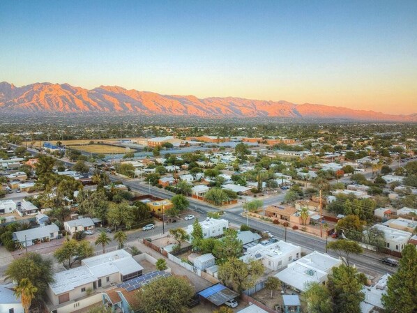 An aerial view of a town with residential areas, roads, and mountains in the background. - Charming Spanish Style Vintage Casita (Tucson)
