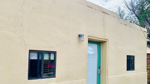 A single-story building with a beige exterior, a green door, and two small windows.