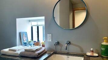 A bathroom with a large mirror, a sink, and a window.