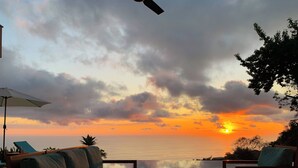 A sunset view from a balcony with outdoor seating and a patio umbrella. - Private Villa Oro Verde, ocean view, luxury (Uvita)