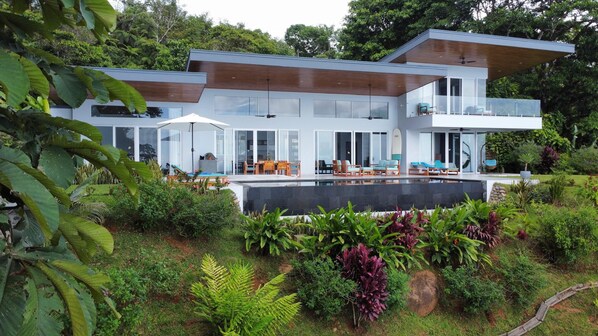 Une maison moderne à deux étages, dotée d’une piscine, d’un espace de détente extérieur et d’un jardin luxuriant.