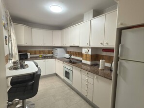 A kitchen with white cabinets, a microwave, a toaster, and a refrigerator. - García Rota Beach by staycare (Rota)