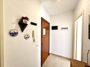 A hallway with a wooden door, a wall-mounted telephone, decorative plates, and a wall-mounted light fixture. - García Rota Beach by staycare (Rota)