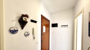 Ein Flur mit einer Holztür, einem an der Wand befestigten Telefon und dekorativen Tellern.