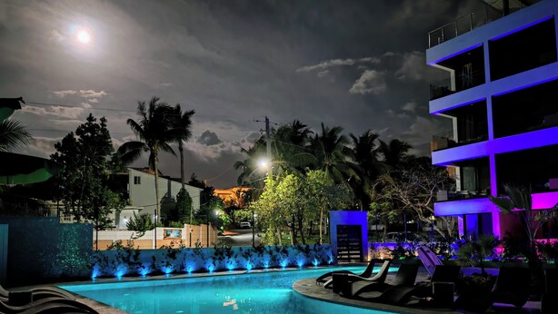A nighttime pool area with lounge chairs and a pool illuminated by blue lights. - Modern Seaview Condo w/ Pool & Balcony – Steps to Beach (Cabarete)