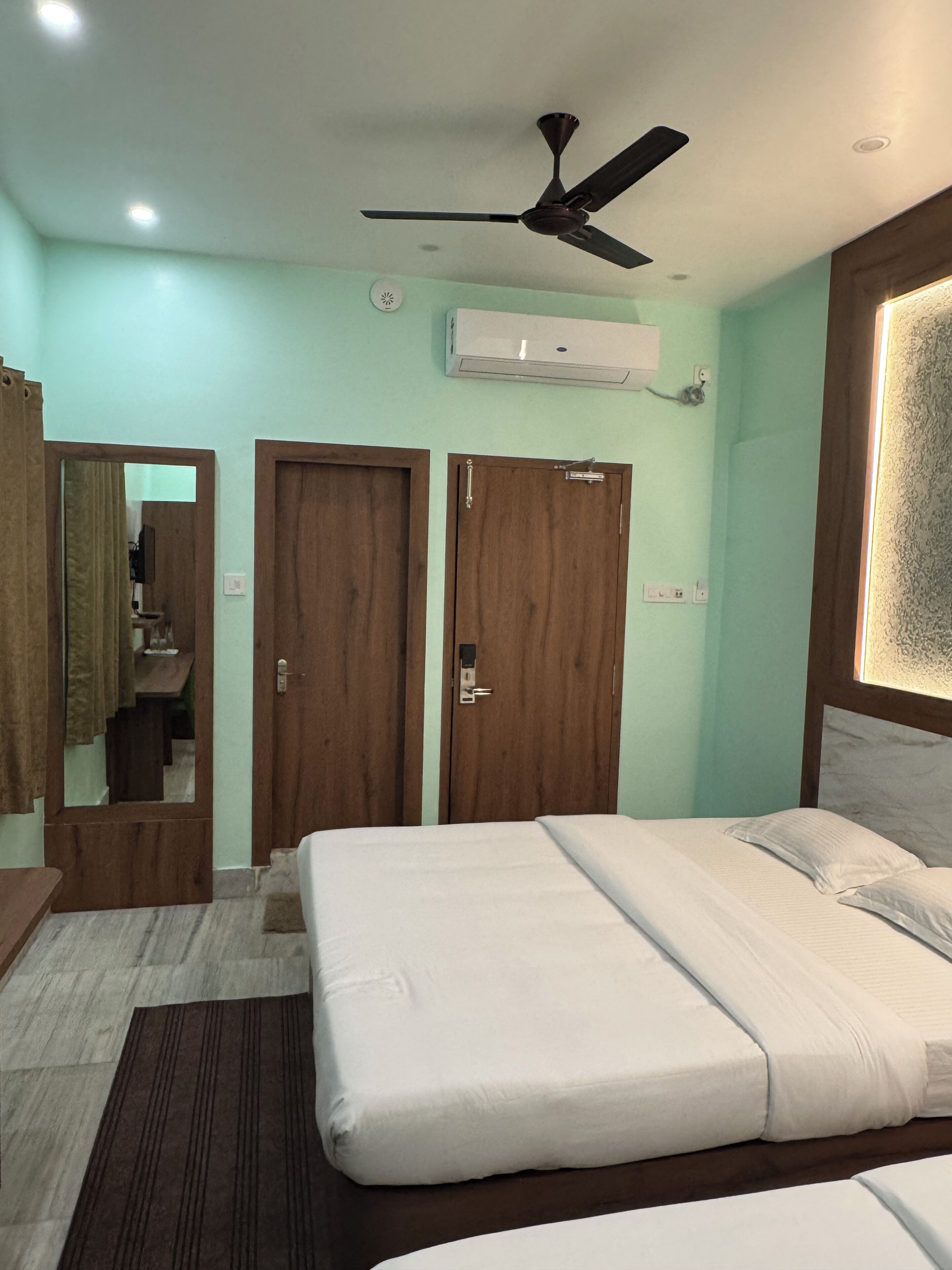 A bedroom with a bed, a ceiling fan, a mirror, and a wardrobe.