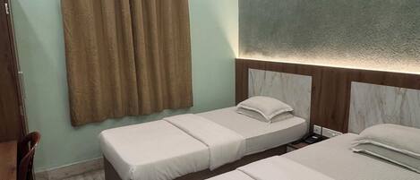 A hotel room with two beds, a ceiling fan, a window with curtains, and a wooden headboard.