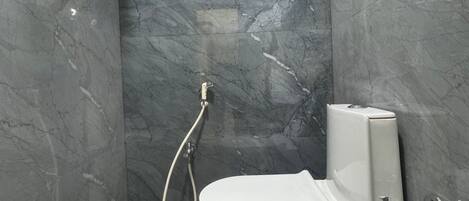 Une salle de bain avec douche, toilettes et murs en marbre.
