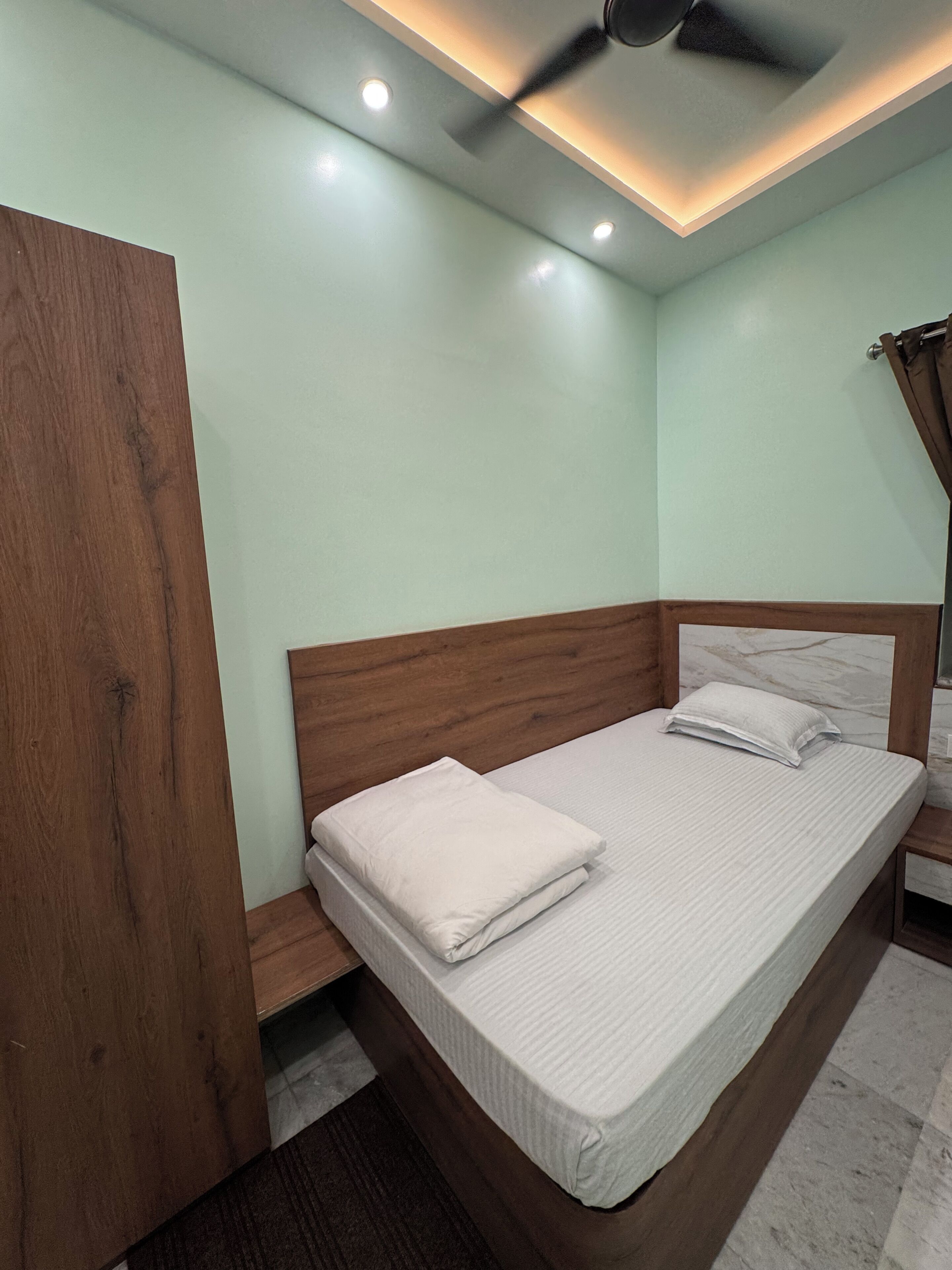 A bedroom with a bed, wooden headboard, and a ceiling fan.