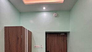 Un couloir avec une armoire en bois, une porte et un luminaire au plafond.