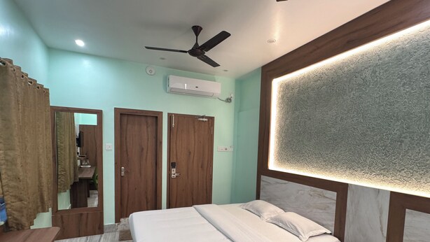 Une chambre d’hôtel avec deux lits, un ventilateur de plafond, un appareil de climatisation et un miroir.
