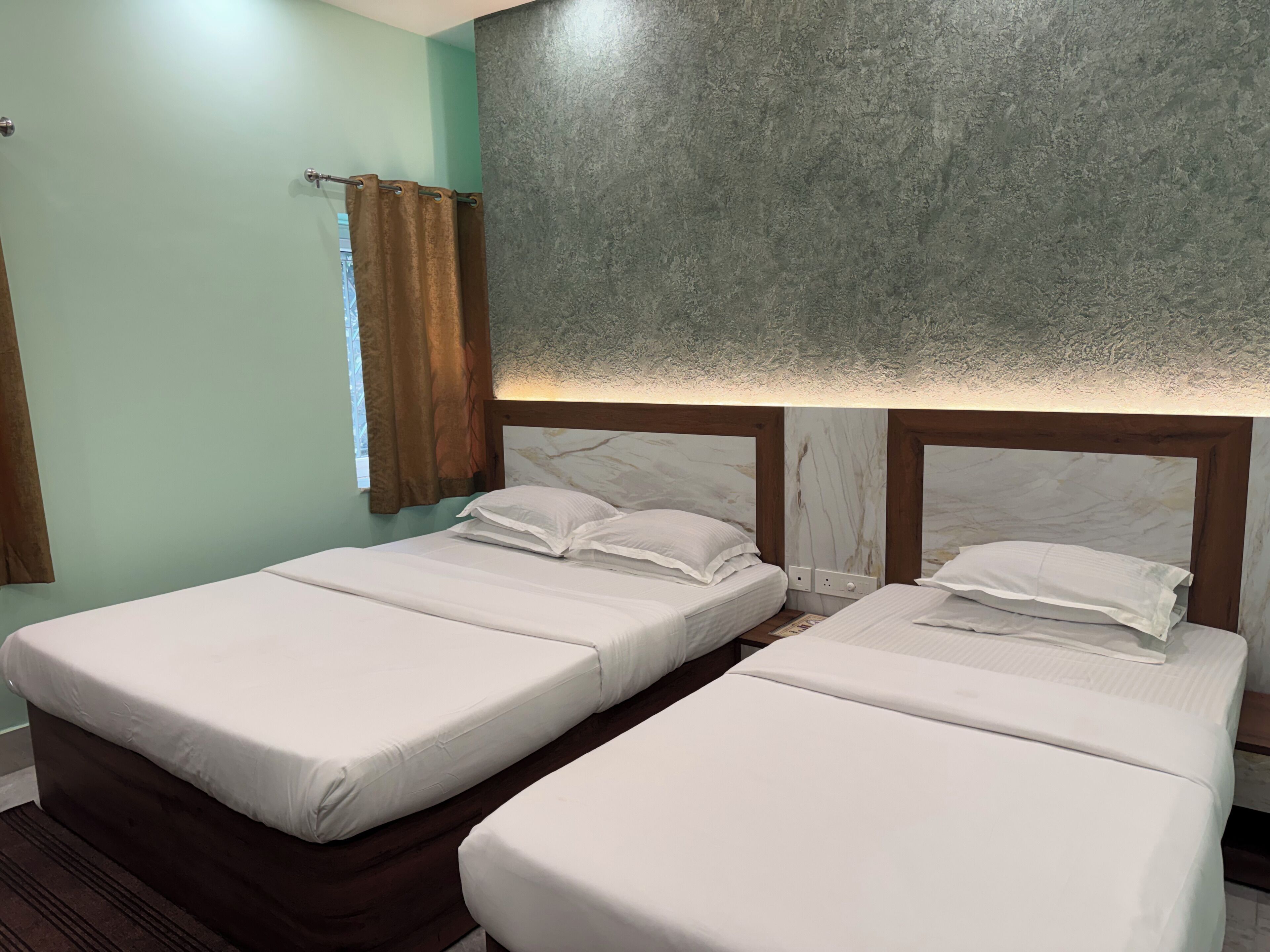 Quarto com duas camas de solteiro, janela com cortinas e parede com textura.