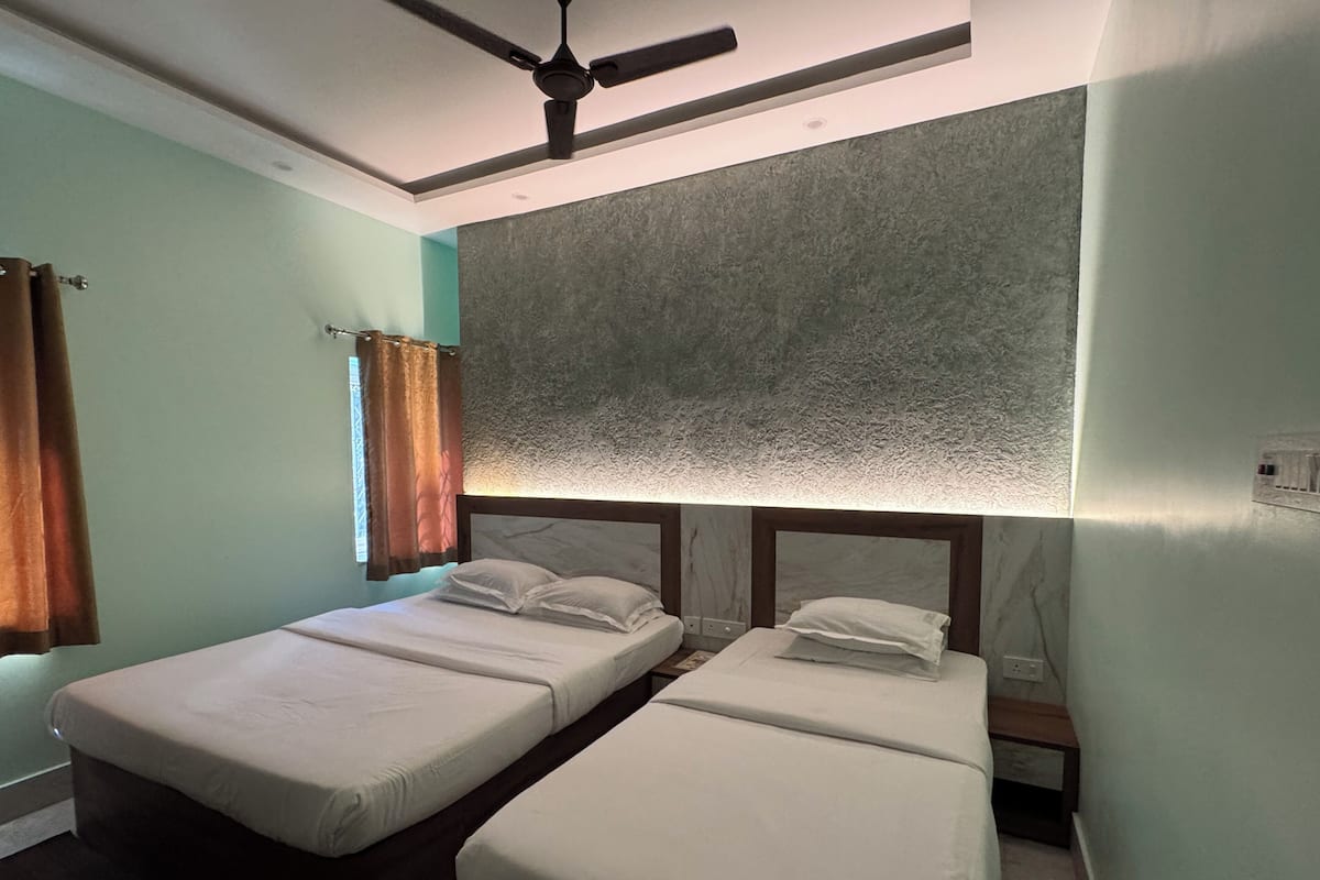 A room with two beds, a ceiling fan, and a textured wall.