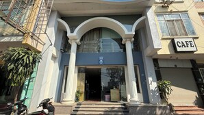 A building with a cafe sign, a staircase leading to the entrance, and a parked motorcycle. - Era Apartment Ho Rua (Hanoi)