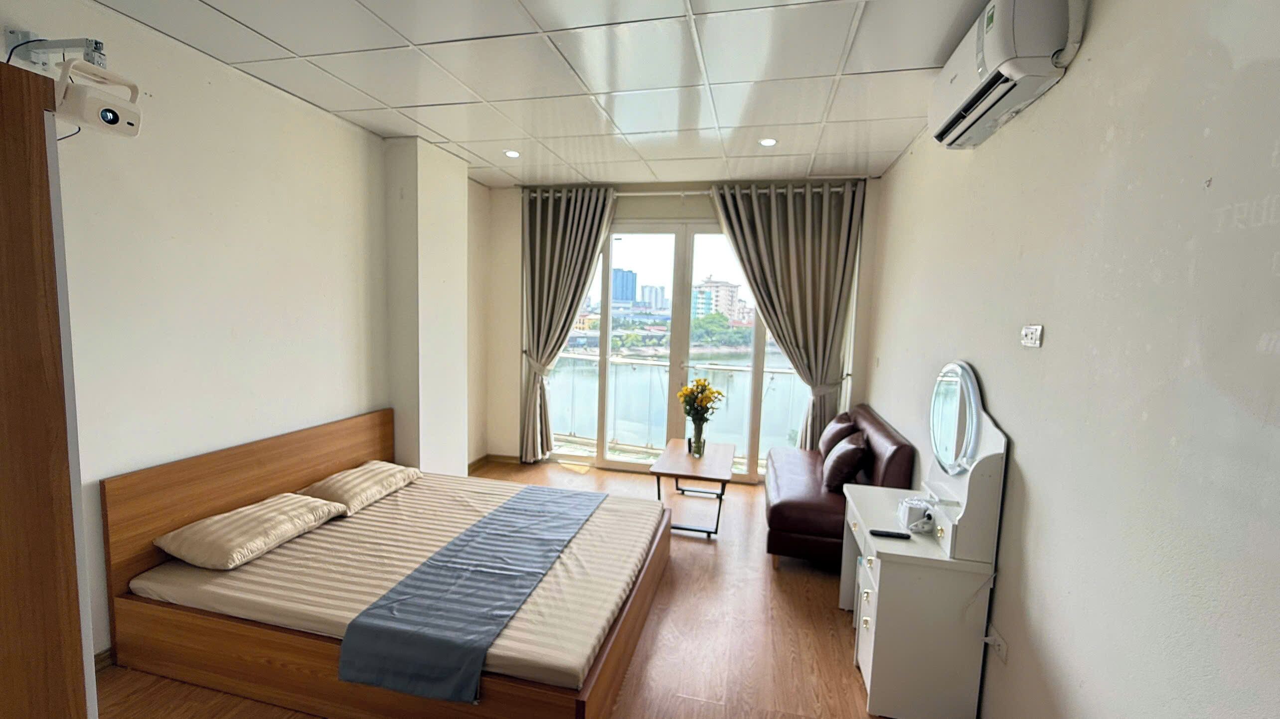 Habitación de hotel con cama, escritorio, silla, espejo y vista a un cuerpo de agua.