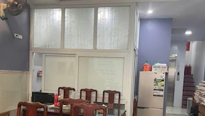 Ein Essbereich mit Holzkstühlen und einem Glastisch, einem Kühlschrank und einem Fenster mit satiniertem Glas.