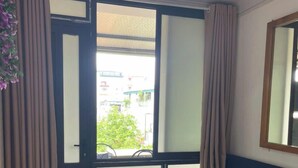 Ein Zimmer mit Holzboden in Schachbrettmuster, einem blauen Sofa, einem Deckenventilator und einem Fenster mit Vorhängen.