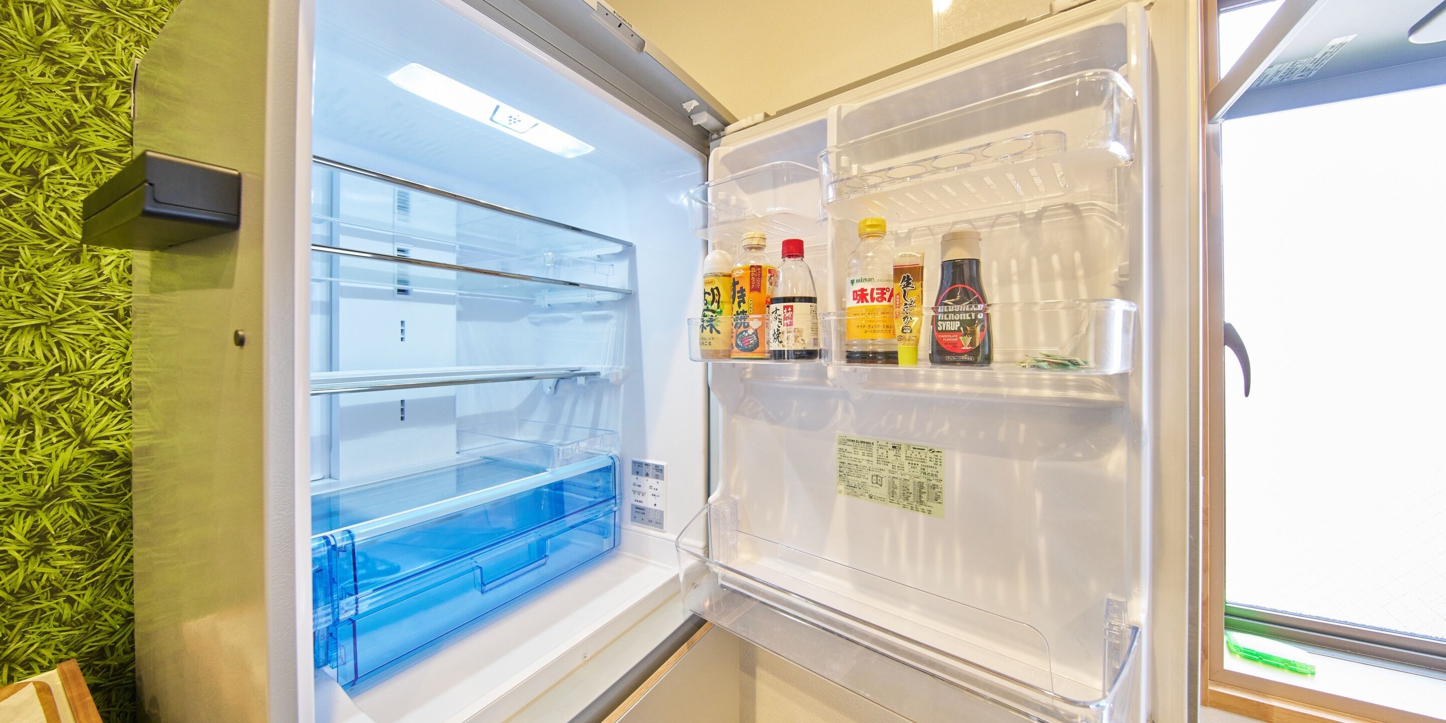An open refrigerator with clear shelves and a blue drawer, containing various bottles and containers.