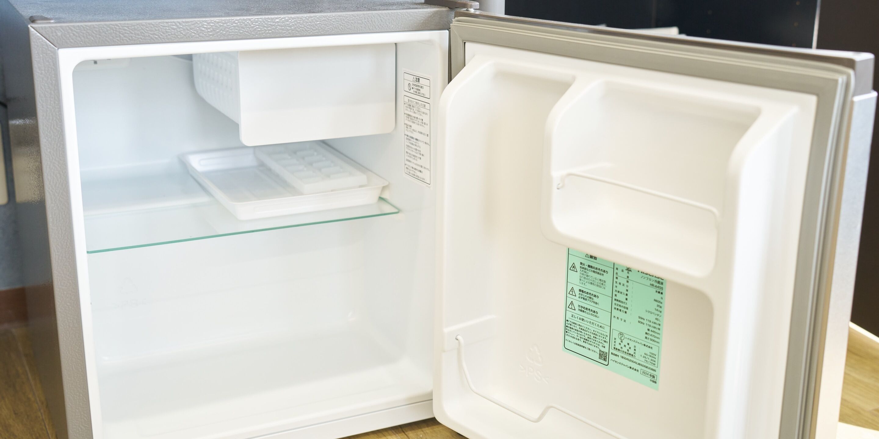 An open refrigerator with a glass shelf and a label on the door.