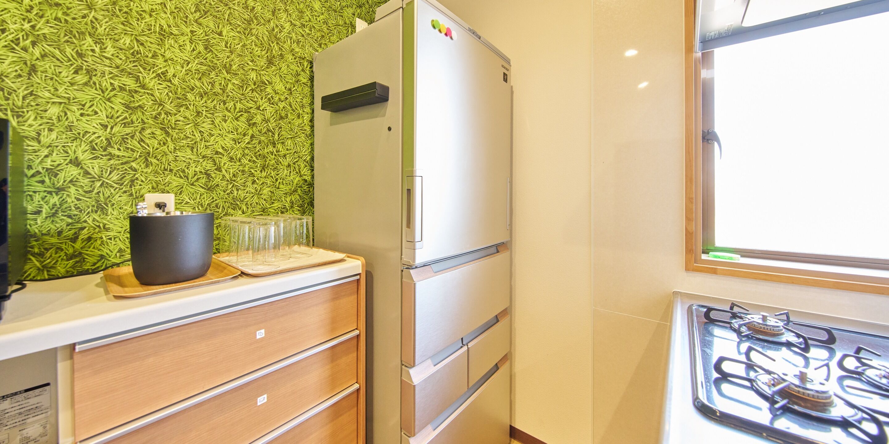 Una cocina con un refrigerador, un armario de madera y una estufa a gas.