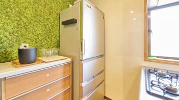 Una cocina con un refrigerador, un armario de madera y una estufa a gas.
