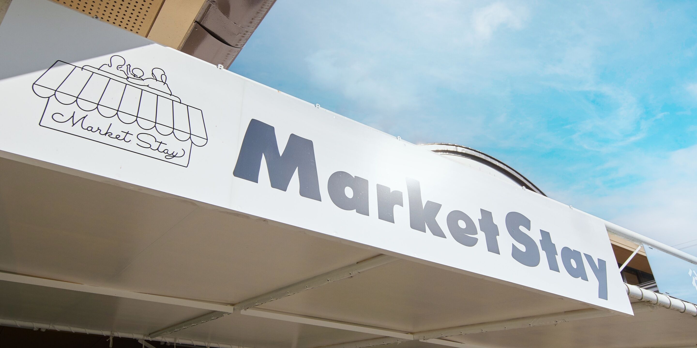 Un letrero con el texto 'MarketStay' y un gráfico de un puesto de mercado.