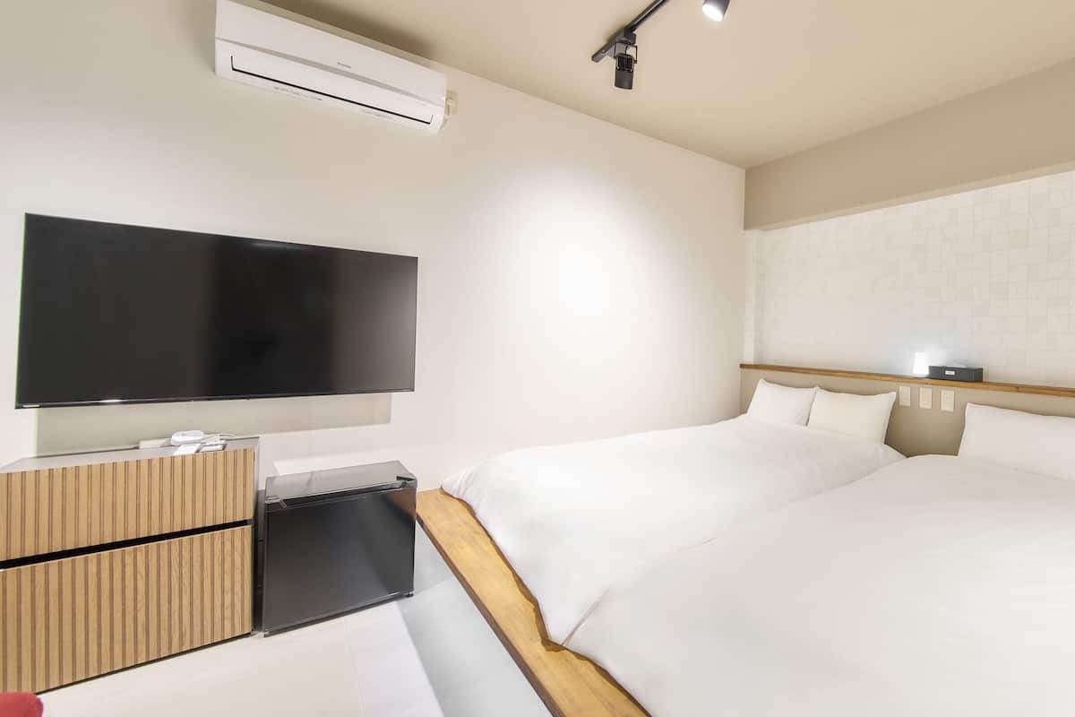 A hotel room with a large flat-screen TV, wooden furniture, and a bed with white bedding.