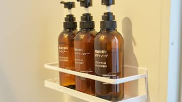 A white shelf with four bottles of orange essential oil soap.