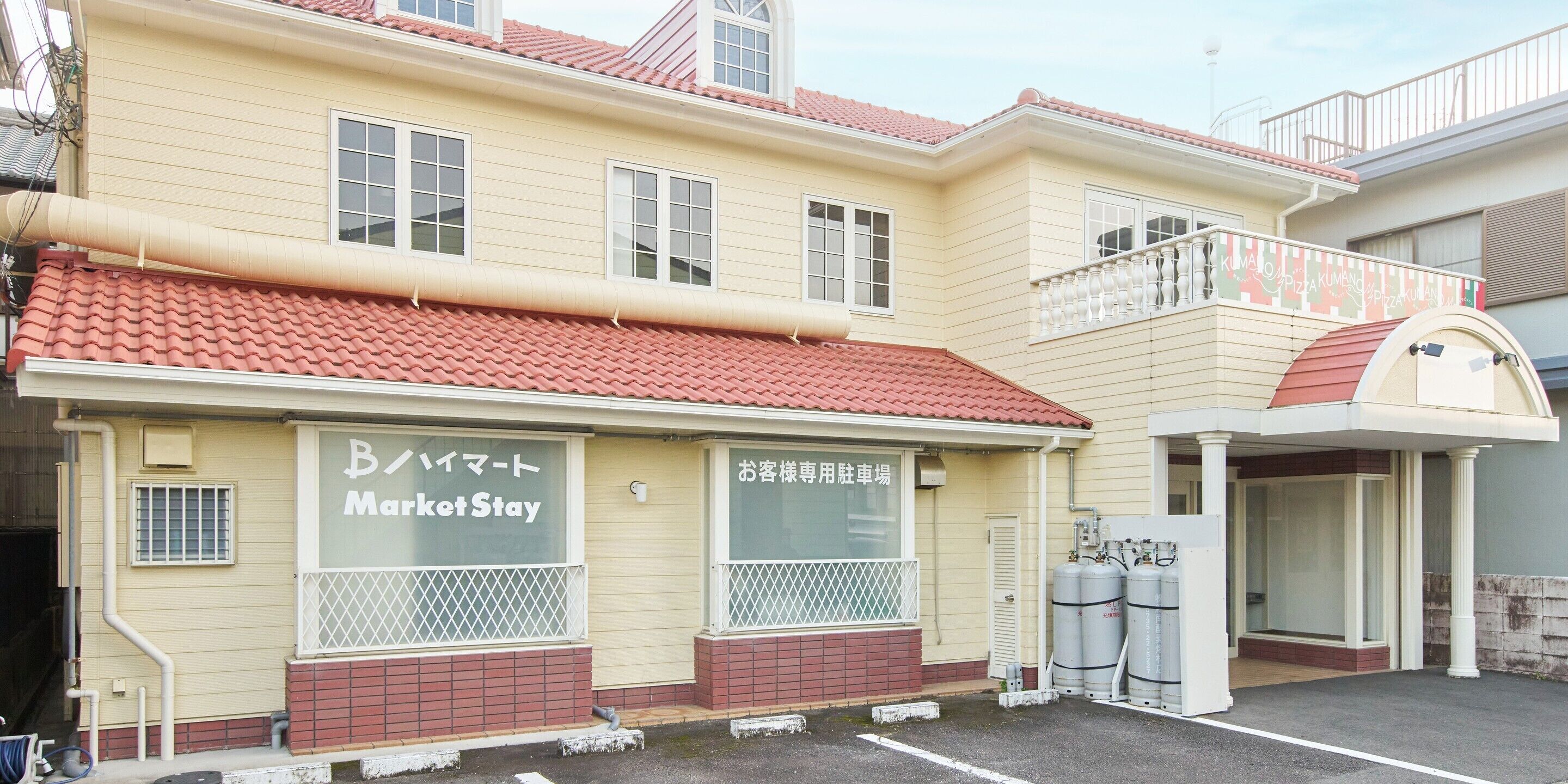 A two-story building with a red-tiled roof, a balcony with a railing, and a sign that reads "Market Stay".