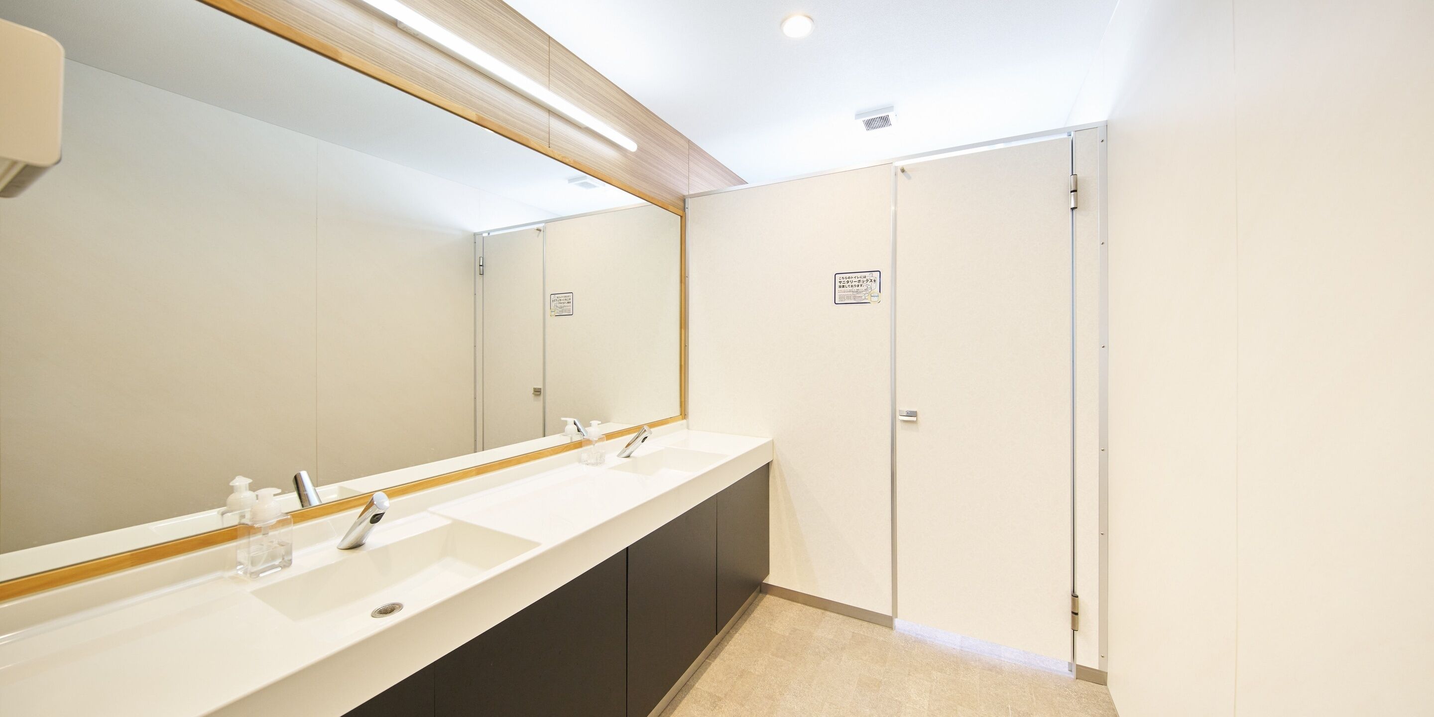 A modern bathroom with a long vanity, two sinks, and a large mirror.