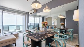 A modern dining area with a central table, teal chairs, and pendant lighting. - Veranda Residence by SEA U PATTAYA (Pattaya)