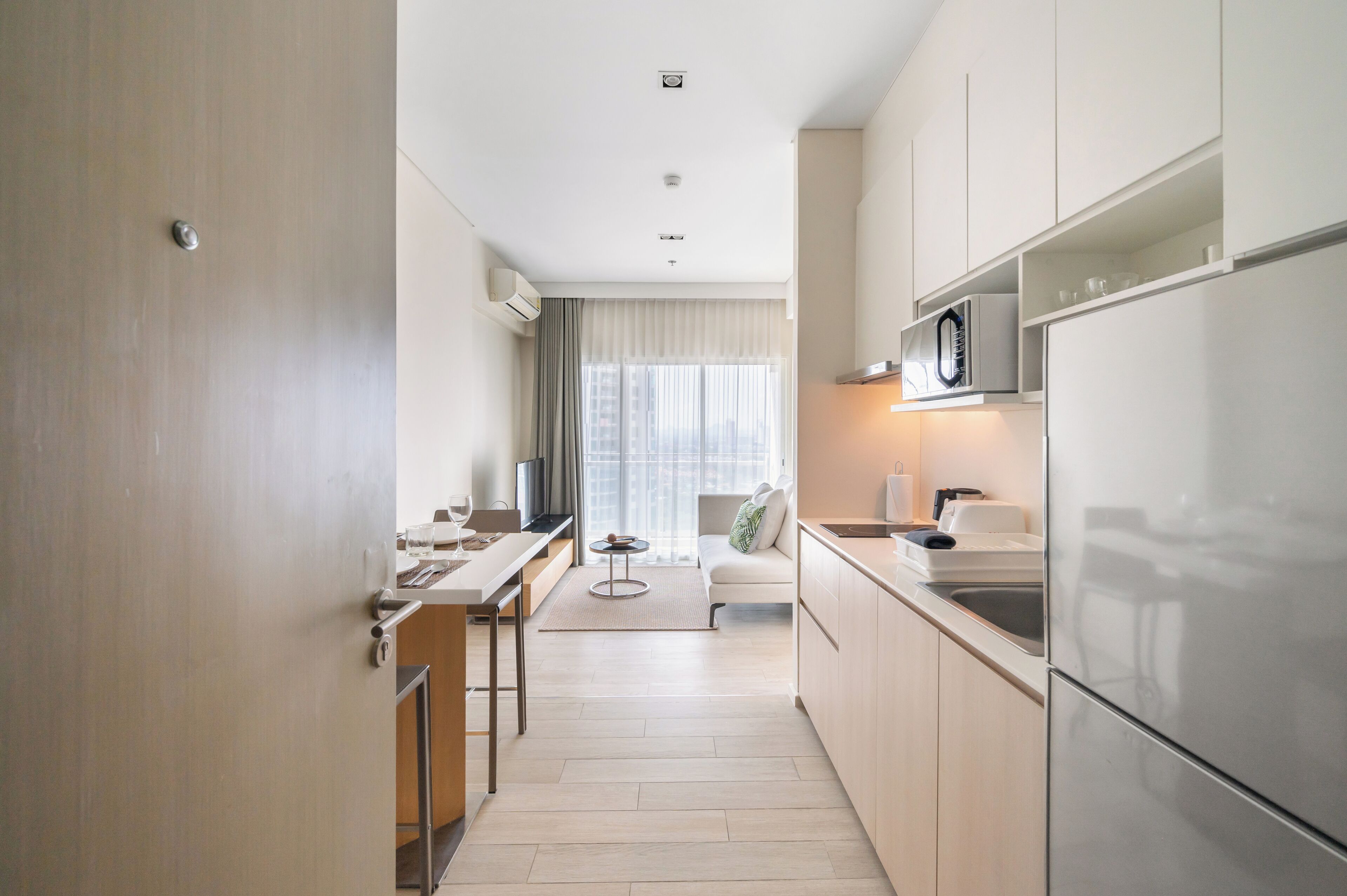 Una cocina moderna con microondas integrado, refrigerador de acero inoxidable y un pequeño comedor con mesa y sillas.