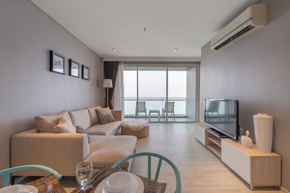 Una sala de estar moderna con sofá, televisión y comedor.