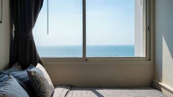 Une chambre avec un lit, une fenêtre avec des rideaux et une vue sur la mer.