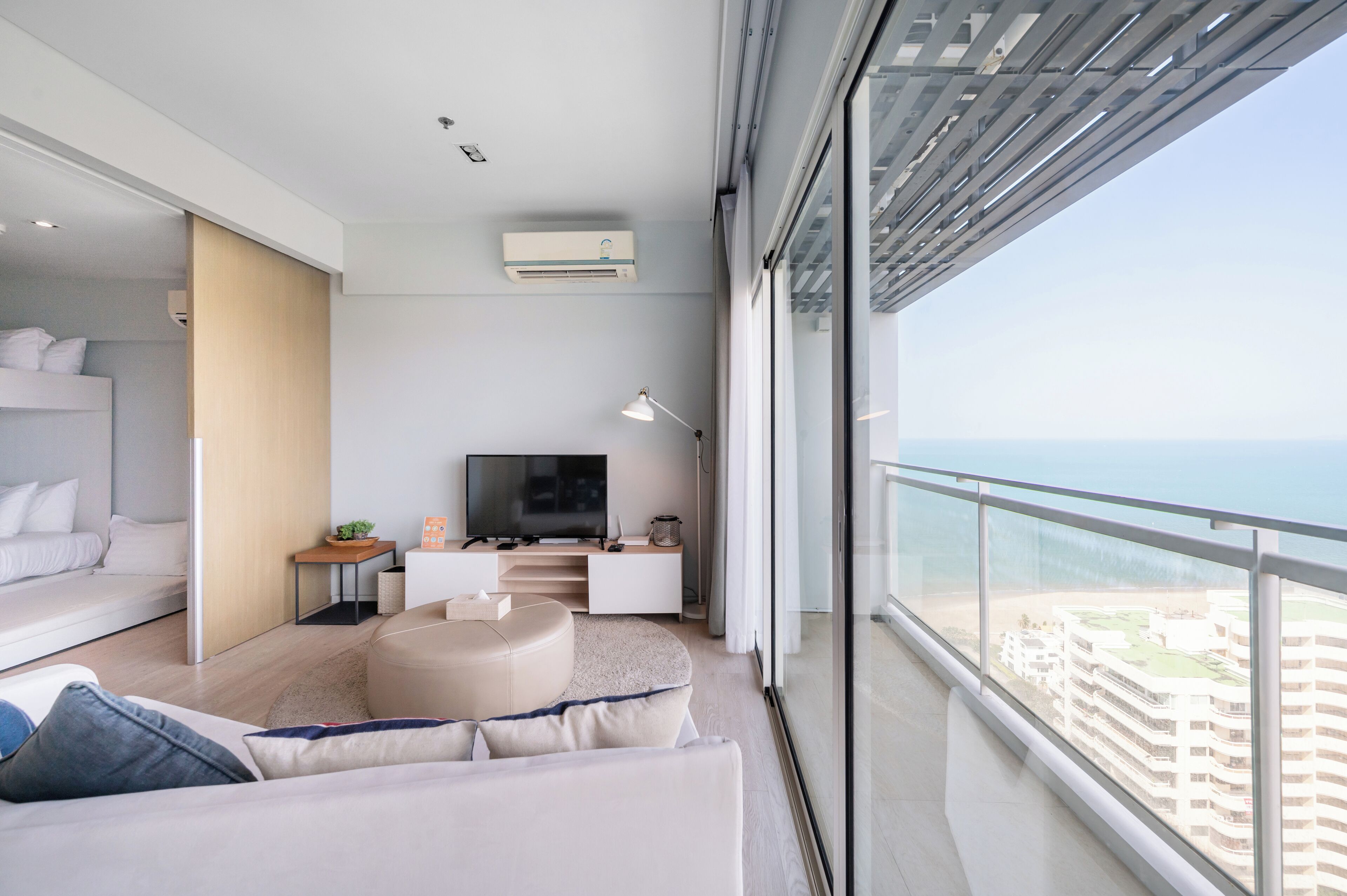 A modern living room with a sofa, TV, and a balcony with a view of the city.