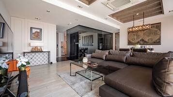 A modern living room with a large sectional sofa, a glass coffee table, and a dining area with a wooden table and chairs.