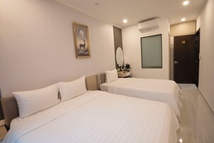 Habitación de hotel con dos camas, un espejo grande, un cuadro y una puerta con un número.