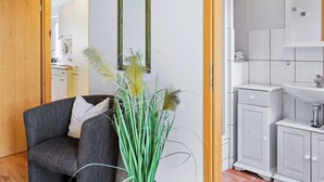 A modern living room with a grey sofa, a wooden door, and a white cabinet with a mirror. - Holiday apartment near the beach with a terrace (Hohenkirchen OT Wahrstorf)