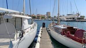Un port de plaisance avec des yachts amarrés, une jetée en bois et des bâtiments en arrière-plan.