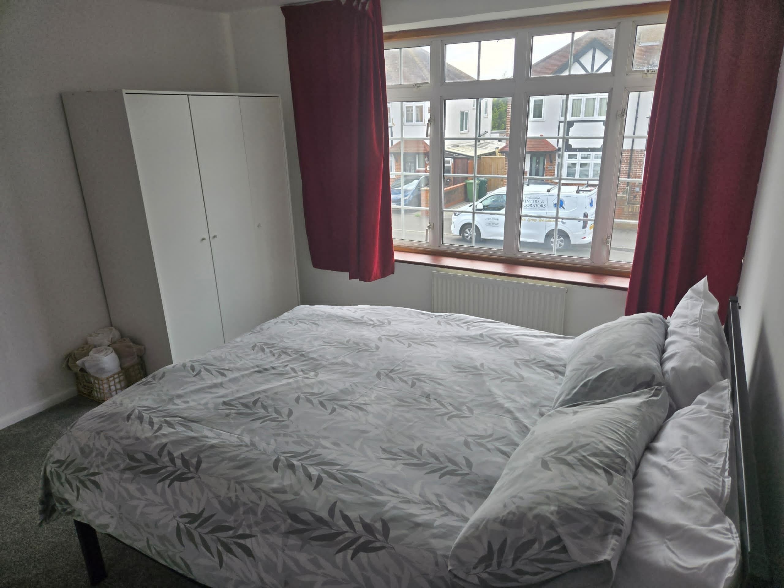 Une chambre à coucher avec un lit, une armoire et une fenêtre avec des rideaux.
